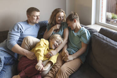 Mann schaut auf Familie lachend auf Sofa - IHF00694