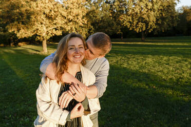 Mann küsst blonde Freundin in öffentlichem Park - IHF00711