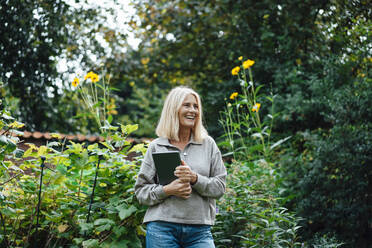 Lächelnde Frau mit Tablet-PC im Garten - JOSEF06100