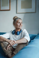 Frau mit drahtlosen Kopfhörern auf dem Sofa sitzend - JOSEF06104