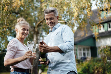 Paar hält Champagnerflöten und Flasche im Hinterhof - JOSEF06109