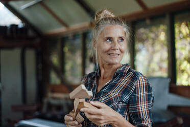 Lächelnde Frau mit Holzwerkzeug im Gartenschuppen - JOSEF06111