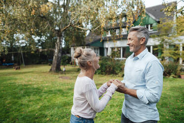 Smiling couple holding each other hands at backyard - JOSEF06121