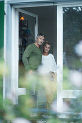 Smiling couple standing together at home entrance - JOSEF06136