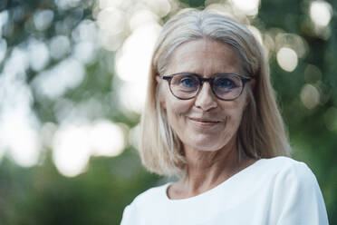 Smiling blond woman with eyeglasses at backyard - JOSEF06139