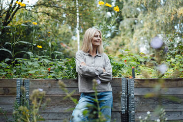 Smiling woman with arms crossed at garden - JOSEF06142