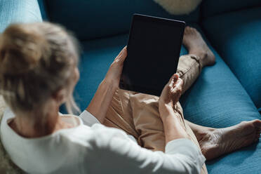 Frau benutzt Tablet-PC auf dem Sofa zu Hause - JOSEF06158