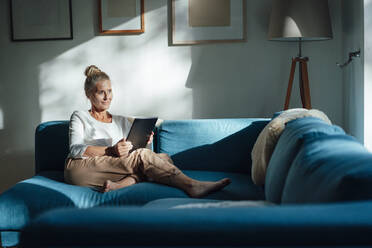 Woman holding tablet PC in living room at home - JOSEF06159