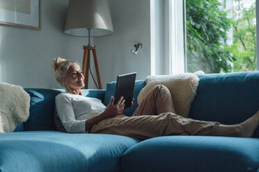 Woman with tablet PC relaxing on sofa at home - JOSEF06160