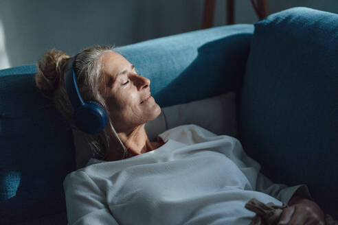 Frau hört Musik über drahtlose Kopfhörer zu Hause - JOSEF06166