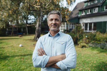 Smiling man with arms crossed at backyard - JOSEF06189