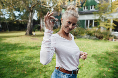 Smiling woman holding house key at backyard - JOSEF06200