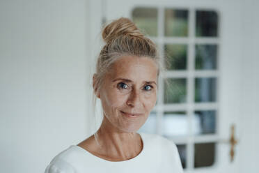 Smiling woman with hair bun at home - JOSEF06218