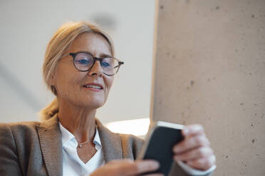 Businesswoman using mobile phone in office - JOSEF06261