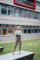 Businesswoman with arms crossed on bench at office park - JOSEF06266