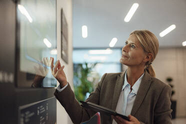 Geschäftsfrau mit Tablet-PC und Blick auf den Bildschirm im Büro - JOSEF06276