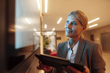 Smiling businesswoman with tablet PC in office - JOSEF06279