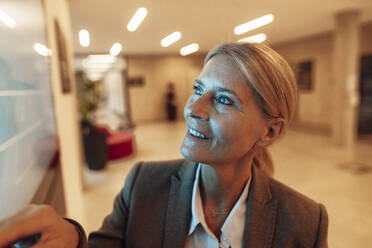 Lächelnde Geschäftsfrau mit Blick auf den Bildschirm im Büro - JOSEF06281