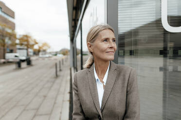 Thoughtful businesswoman looking away on footpath - JOSEF06308