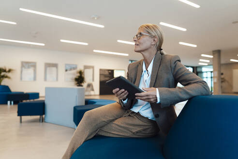 Geschäftsfrau hält Tablet-PC auf Sofa in Lobby - JOSEF06310