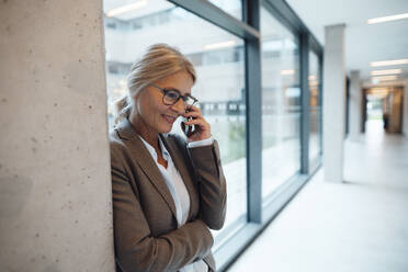 Businesswoman talking on mobile phone in office - JOSEF06351