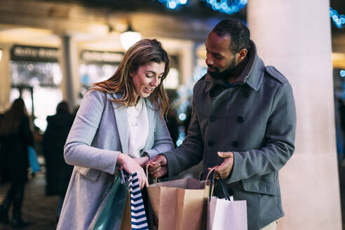 Frau diskutiert mit Mann mit Einkaufstüten auf dem Weihnachtsmarkt - ASGF01856