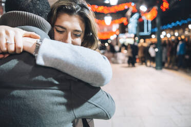 Couple embracing each other at illuminated Christmas market - ASGF01860