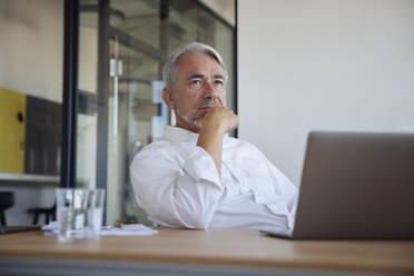 Mature businessman with laptop on table contemplating in office - RBF08382