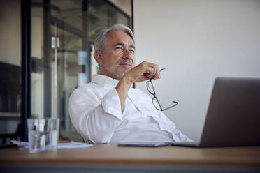 Businessman with eyeglasses contemplating in office - RBF08395