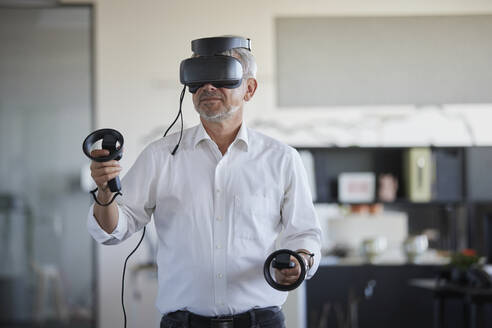 Geschäftsmann spielt mit virtuellem Headset am Arbeitsplatz - RBF08408