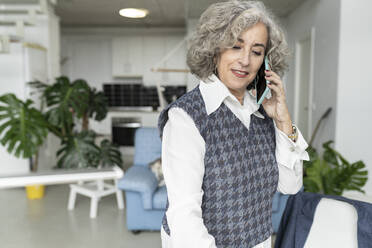 Senior businesswoman talking on mobile phone at home office - JCCMF04778