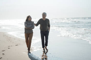 Senior man with daughter walking together at beach - GUSF06568