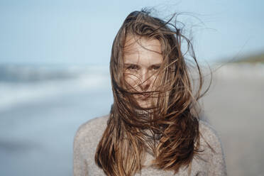 Junge Frau mit zerzaustem Haar am Strand - GUSF06584