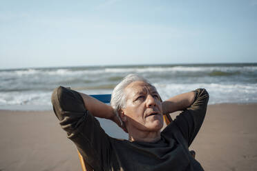 Älterer Mann entspannt sich am Strand an einem sonnigen Tag - GUSF06600
