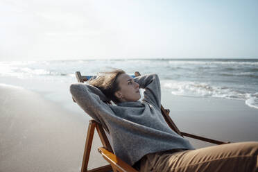 Young woman relaxing on chair at beach - GUSF06605