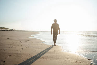 Man walking by seashore at beach - GUSF06637
