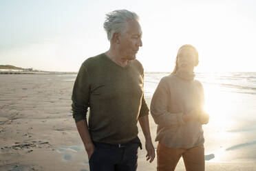 Vater und Tochter gehen am Strand spazieren und unterhalten sich - GUSF06647