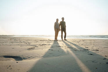 Tochter steht mit Vater im Sand am Strand - GUSF06651