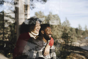 Smiling couple looking away seen through window - MASF27204