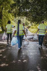 Multirassische weibliche Freiwillige, die mit Plastik im Park spazieren gehen - MASF27318