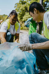 Male environmentalist picking up plastics with female volunteer - MASF27333