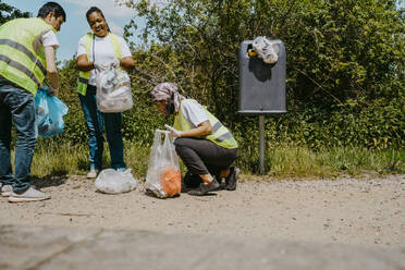 Männliche und weibliche Aktivisten sammeln an einem sonnigen Tag Plastik ein - MASF27339