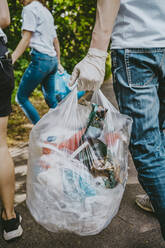 Female and male environmentalists cleaning garbage in park - MASF27363