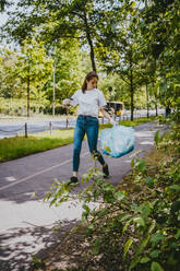 Young female volunteer cleaning plastic waste in park - MASF27367