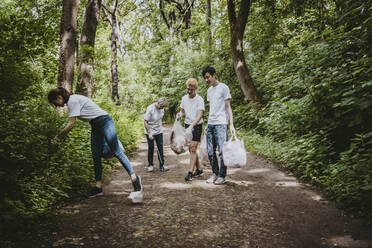 Male and female environmentalists picking up garbage in park - MASF27372