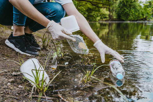 Niedriger Ausschnitt einer freiwilligen Helferin, die einen Teich im Park von Plastikmüll befreit - MASF27376