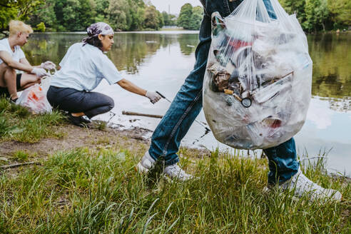 Umweltschützerinnen und Umweltschützer säubern einen Teich im Park von Plastikmüll - MASF27379