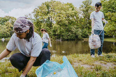 Männliche und weibliche Freiwillige reinigen Plastik in der Nähe des Teiches - MASF27383