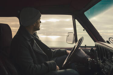 Mature man looking through window while sitting in camping van - MASF27406