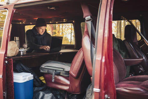Businessman using laptop while working in motor home - MASF27426